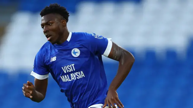 Ade Gbadehan running on the pitch wearing blue Cardiff City kit.