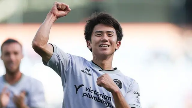 Yu Hirakawa celebrates Bristol City's late win at Burnley with travelling fans, punching the air wearing City's silver away kit
