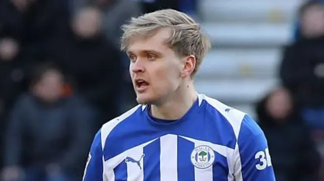 Matt Smith in a blue and white Wigan Athletic jersey during a match.