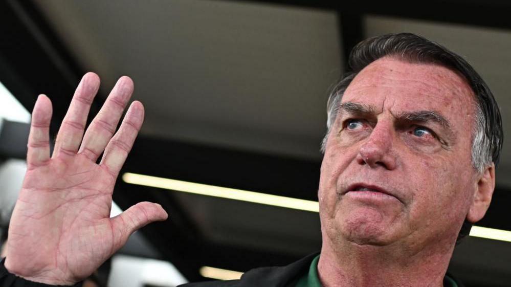 Brazil's former president Jair Bolsonaro (2019-2022) waves as hearrives at Brasilia airport, in Brasilia, Brazil, 25 March 2025.