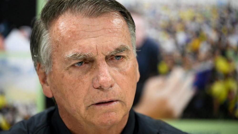 A close-up image of former Brazilian President Jair Bolsonaro shows him in a black top looking ahead