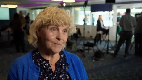 Jo Hamilton, who has blonde curly hair, speaks on camera to the BBC