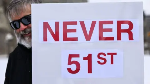 Man holding banner saying 'NEVER 51ST' in red lettering