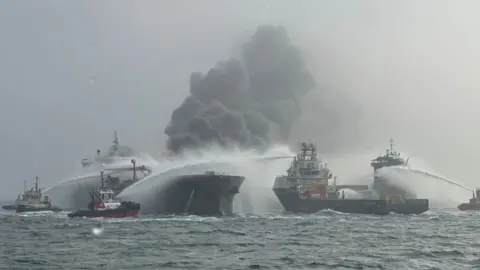 Fire crews extinguishing a fire on two ships at sea