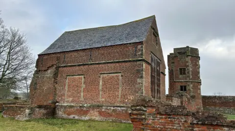 Skillington Workshop Ltd An old brick chapel with a pitched roof - next to a tower and low walls 