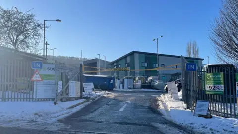 The entrance to Elland Household Waste Recycling Centre, with snow on the ground outside.