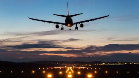 A plane comes in to land on a runway at night.