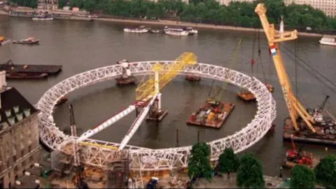 The London Eye ferris wheel laying on barges on the River Thames as its lifted into place in 1999