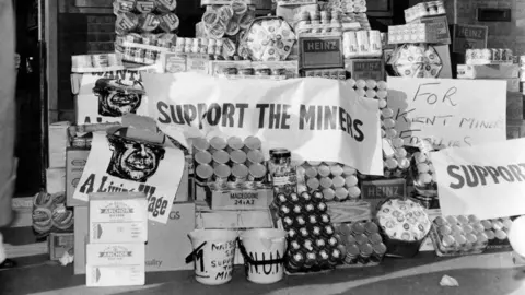 Getty Images Lots of food is piled together with banners drapped over it, reading support for miners. 