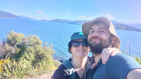 A young couple smiles while taking a selfie.