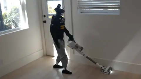 A robot holding a hoover and vacuuming the floor.