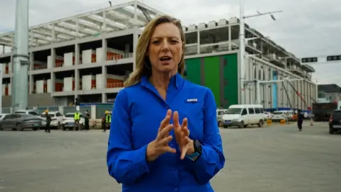 BBC correspondent Laura Bicker wearing a blue shirt standing outside a construction site