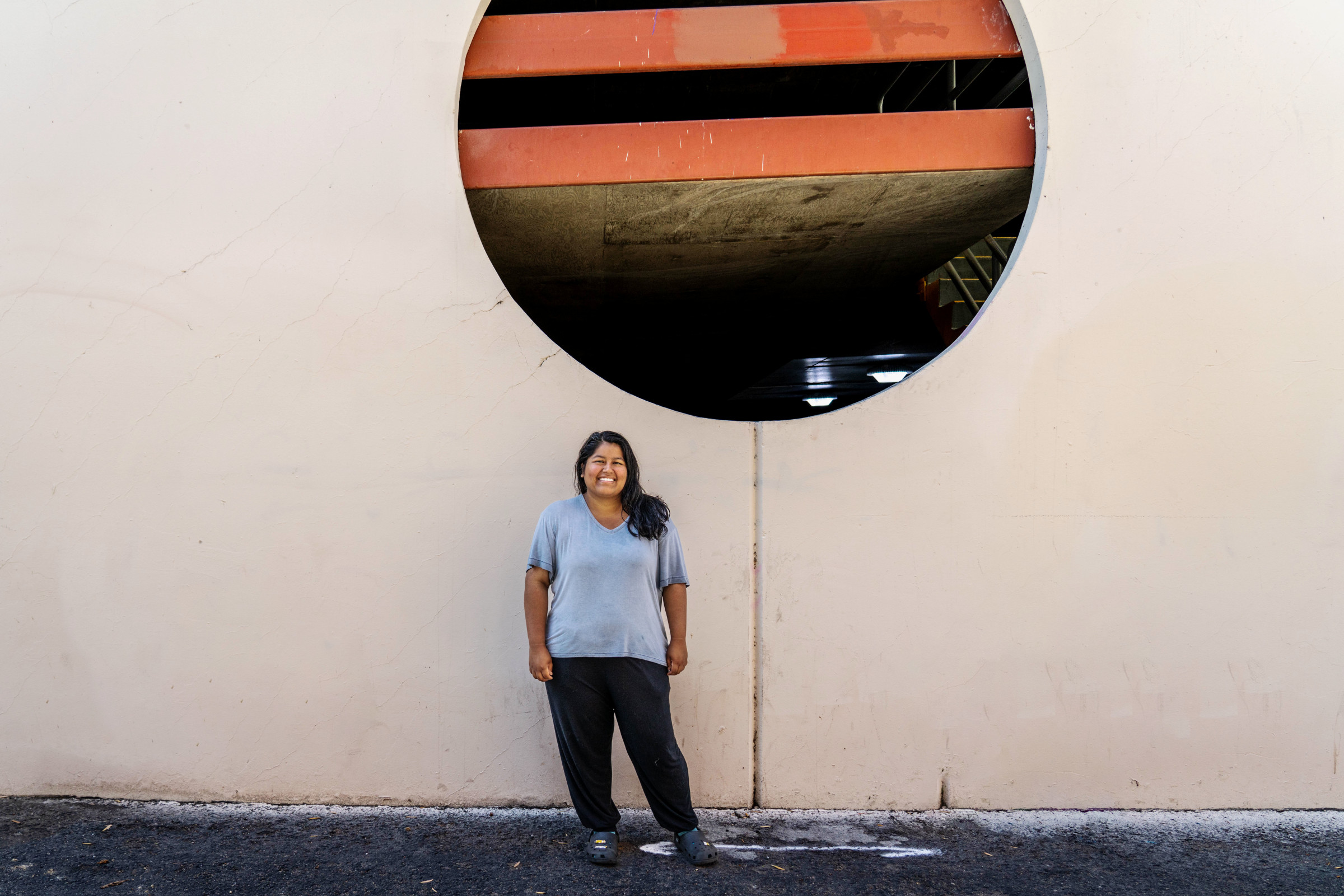 Author Frances smiling at the camera outside, under a large circular window 