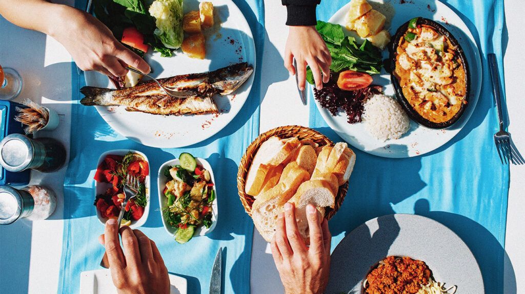 Top view of dinner table with fish, salad, bread, spaghetti and chicken-1