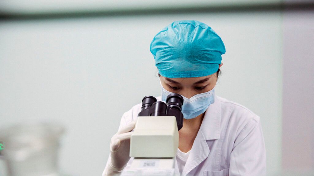 Doctor in the lab looking into a microscope eye piece