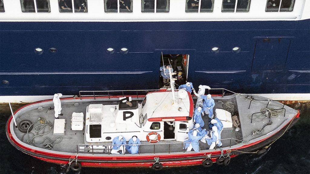 Health personnel in PPE assist hantavirus patients onto a boat