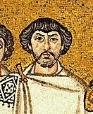 A close up photograph of a mosaic of a person painted on a golden colored background. The person has a white cloth covering up his upper body till the neck, an embroidered pattern on his right shoulder, wavy hair, a stubble beard and a moustache