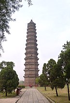 A thin, thirteen story brick building with small, slightly curved eaves between each story. The bricks are a dark grey color, resembling the color of iron.