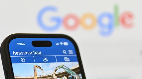 Smartphone mit hessenschau-App vor Bildschirm mit Google-Schriftzug